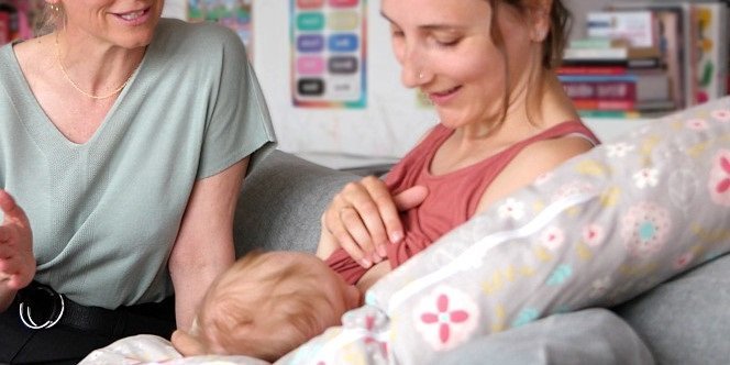 Zwei Frauen sitzen auf dem Sofa, eine stillt ein Baby. Die andere spricht mit ihr.. Artikel "Stillförderung als lohnendes Investment für alle" öffnen.