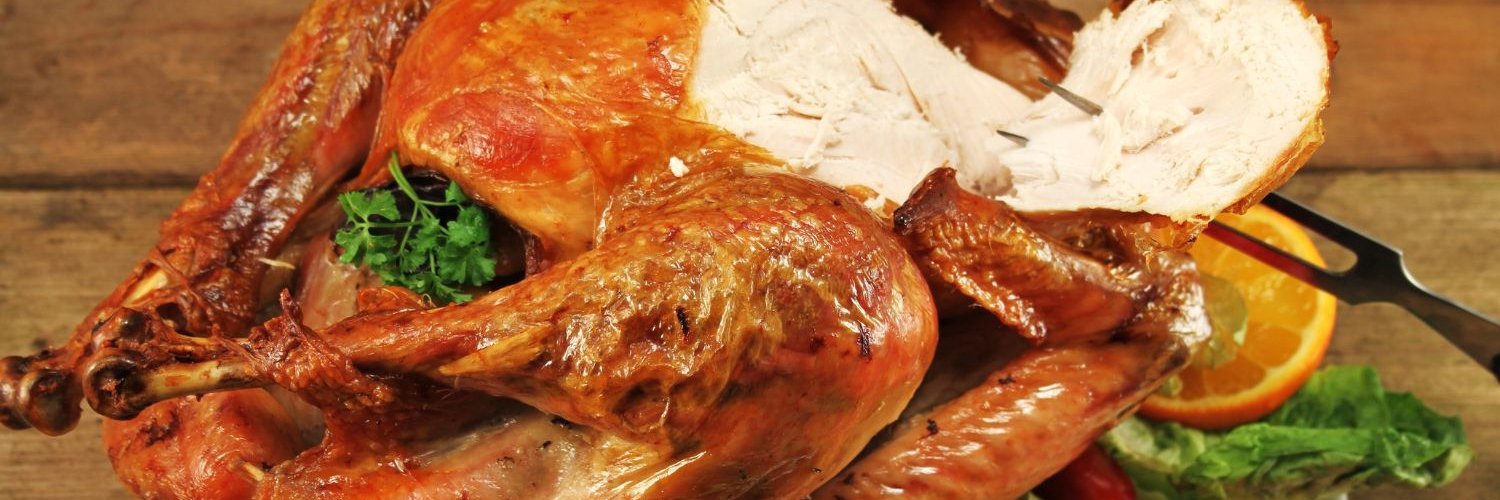 Von einem gebratenen Puter ist eine Scheibe Brust abgeschnitten und auf eine Fleischgabel gespießt.