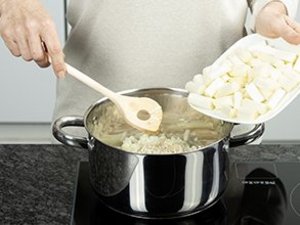 eine Person gibt die Spargelstücke in den Topf