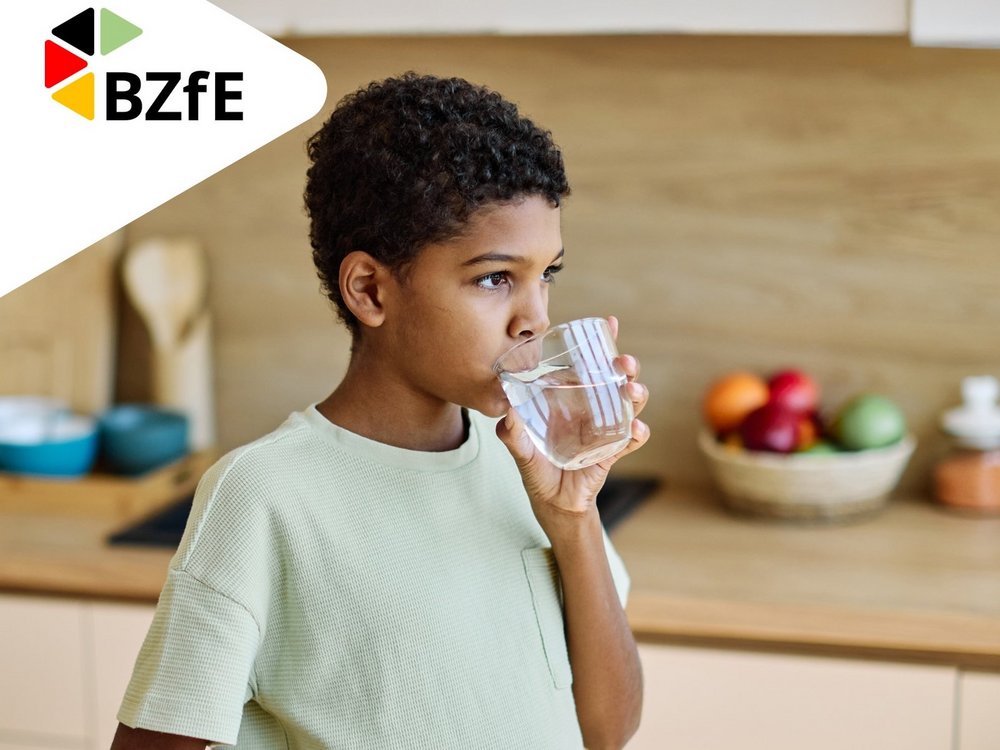 Ein Junge trinkt ein Glas Wasser.