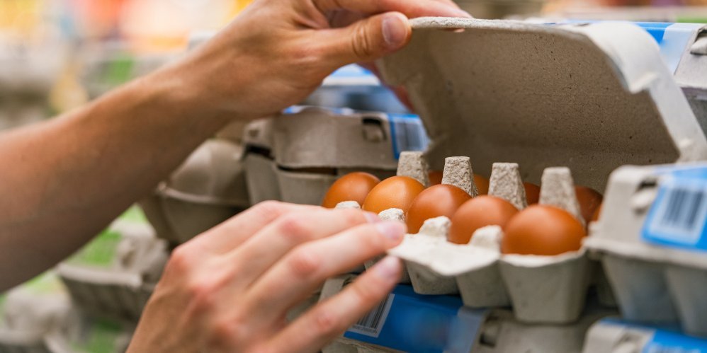 Person öffnet Eierkarton im Supermarktregal.. Artikel "Eier: Vom Stall in den Handel" öffnen.