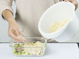 Eine Person verteilt Streusel über Rhabarber.