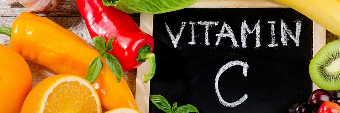 Eine Kreidetafel mit der Aufschrift Vitamin C auf einem Haufen Gemüse und Obst.