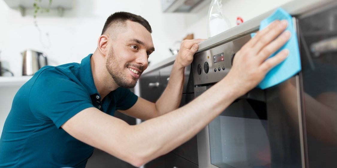 Ein Mann putzt einen Herd mit einem Lappen.. Artikel "Hygiene" öffnen.