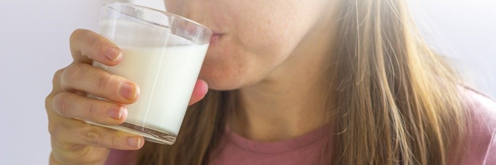 Eine Frau trinkt Buttermilch oder Kefir aus einem Glas. 