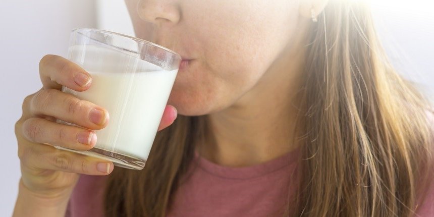 Eine Frau trinkt Buttermilch oder Kefir aus einem Glas. . Artikel "Buttermilch und Kefir" öffnen.