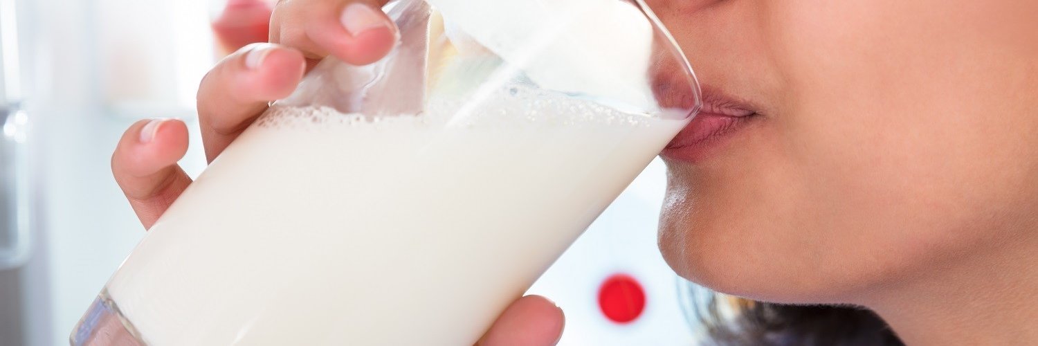 Eine Frau trinkt Milch aus einem Glas.