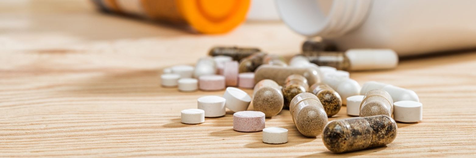 Es liegen verschiedene Dosen und Tabletten Nahrungsergänzungsmittel auf dem Tisch.