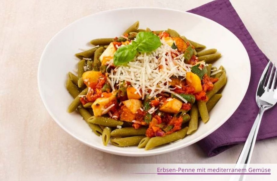 Teller mit grünen Nudeln aus Erbsen, Gemüse und geriebenem Parmesan.