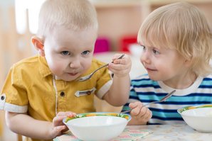 Zwei kleine Jungs begutachten skeptisch einen Löffel mit Essen