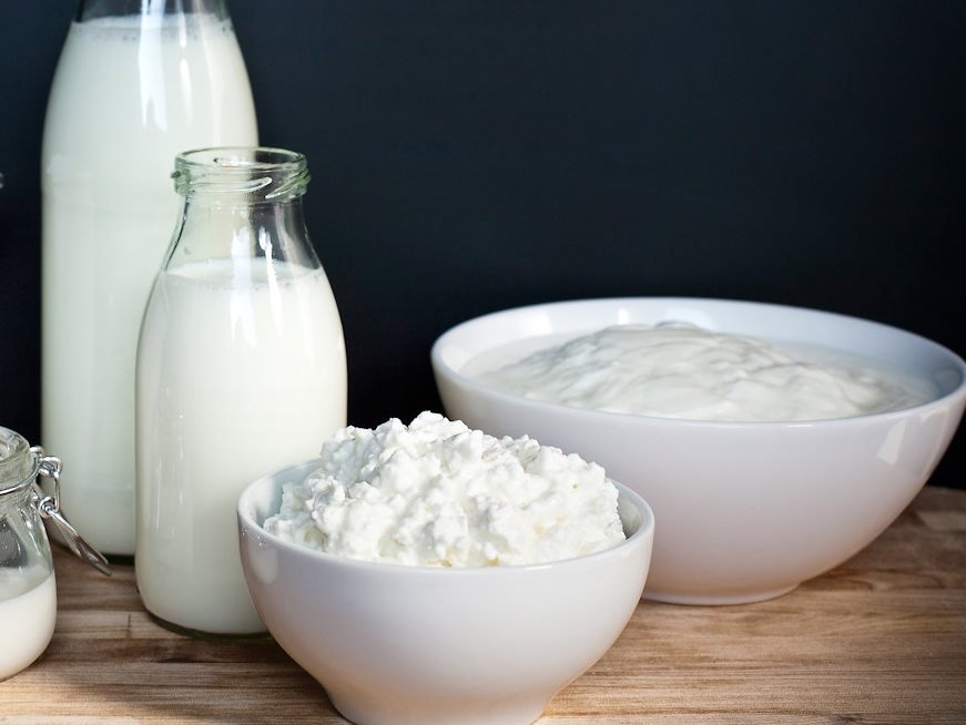 Milch und Milchprodukte in Glasflaschen und weißen Gefäßen.