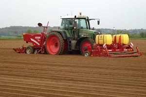Traktor mit angebauten Geräten fährt über Acker