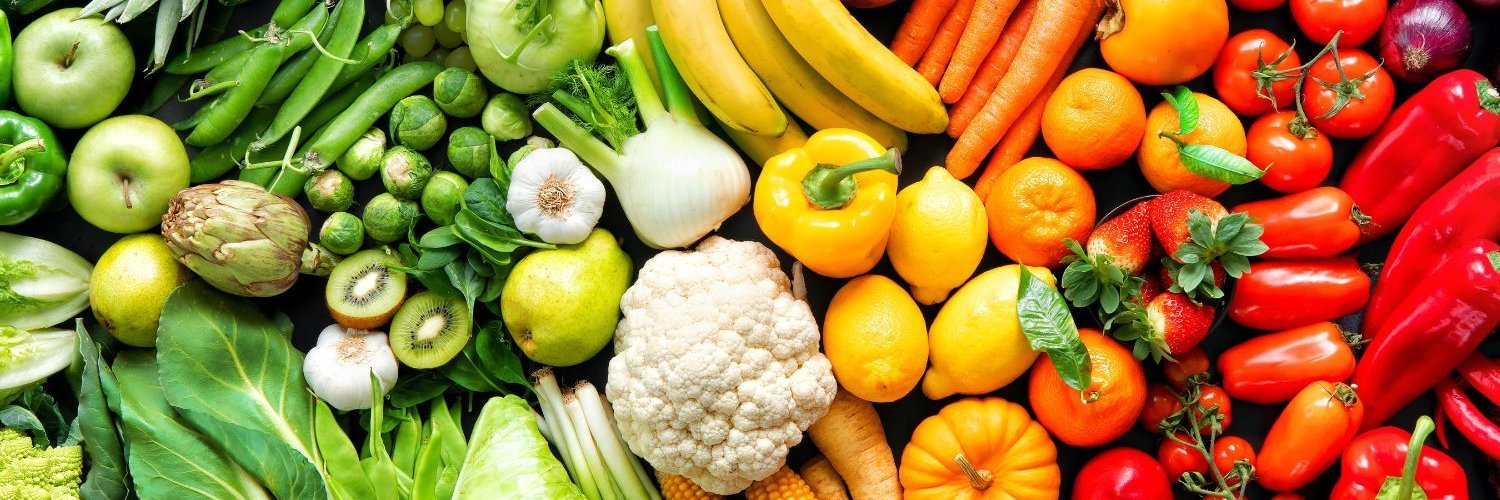 Das Bild ist ausgefüllt mit Obst, Salat und Gemüse. Dabei verändert sich die Farbe von links nach rechts über Grün, zu Weiß, dann Gelb, Orange und Rot mit den passenden Lebensmitteln.