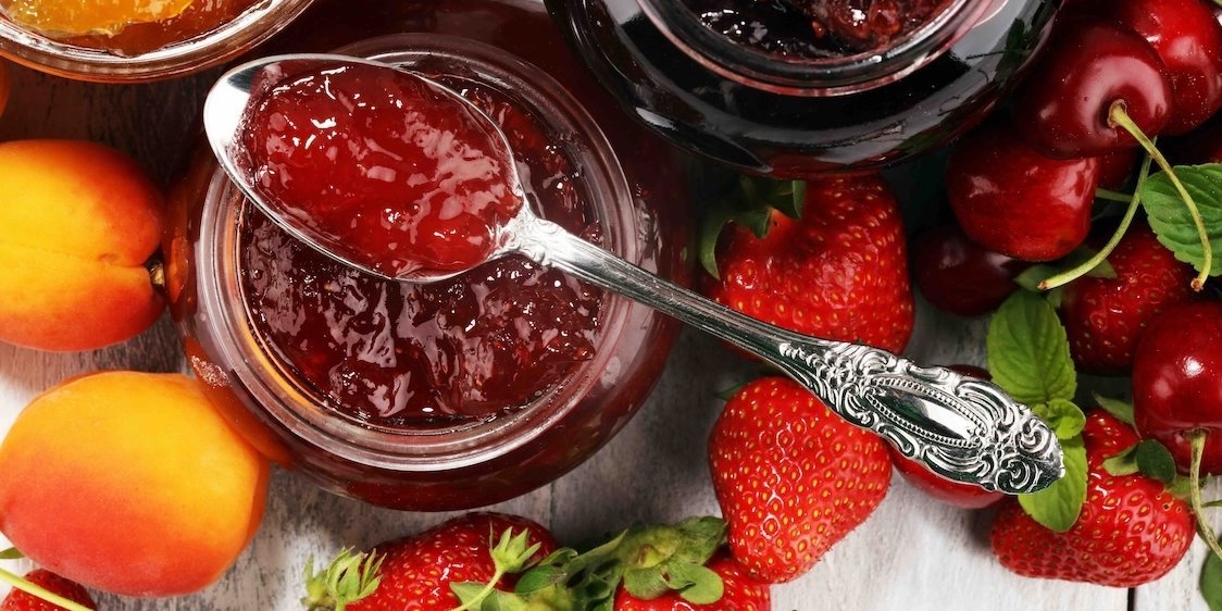 Geöffnete Marmeladengläser in einem appetitlichen Ambiente mit frischen Früchten.. Artikel "Obst einkochen" öffnen.