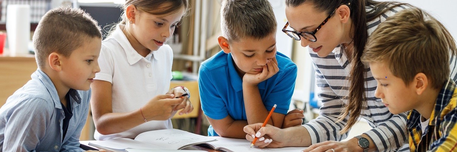 Eine Lehrerin, drei Schüler und eine Schülerin sitzen an einem Tisch und arbeiten in einem Unterrichtsmaterial. 