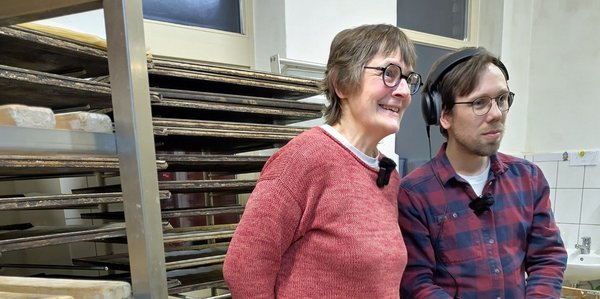Eine Frau und ein Mann stehen vor Regalen.