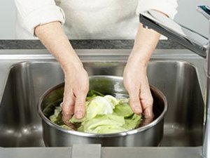 Eine Person wäscht Salat.