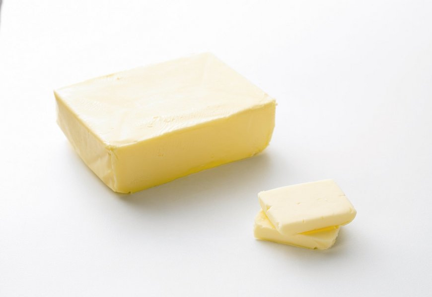 Großes Stücl Butter mit zwei kleinen Stücken davor.