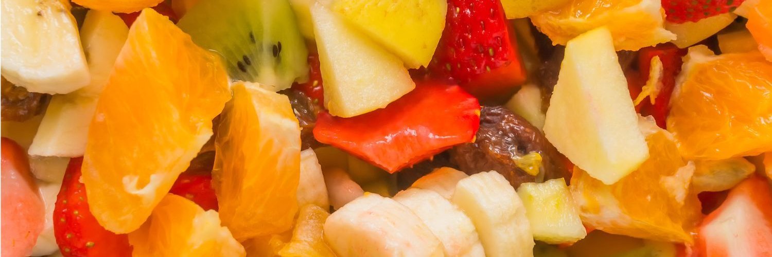 Die Bildfläche ist ausgefüllt mit in Stücke geschnittenen Äpfeln, Bananen, Orangen, Kiwis und Erdbeeren.