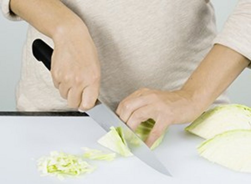 eine Person schneidet den Weißkohl in Streifen.