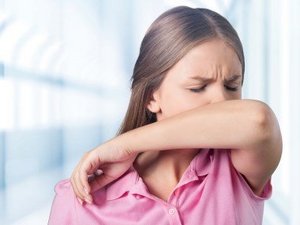 Eine Frau niest in ihre Armbeuge.