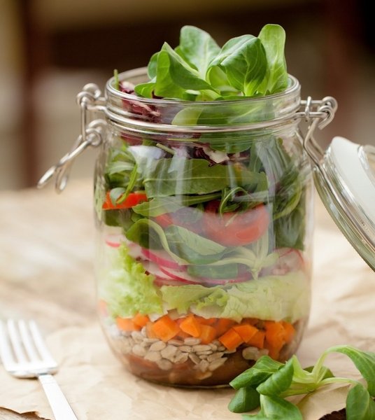Zutaten für einen Salat sind in einem Einmachglas geschichtet.