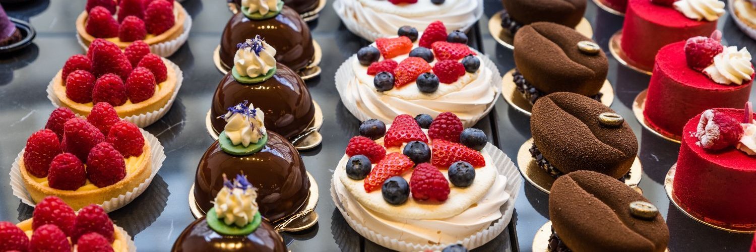 In der Theke eine Konditorei liegen verschiedene Törtchen mit Obst, Schokolade und Sahne. 