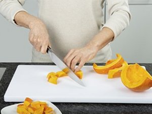 Eine Person schneidet den Kürbis in Würfel.