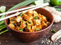 Eine Schüssel mit gebratenem Tofu mit Sesam und Frühlingszwiebeln ist abgebildet.