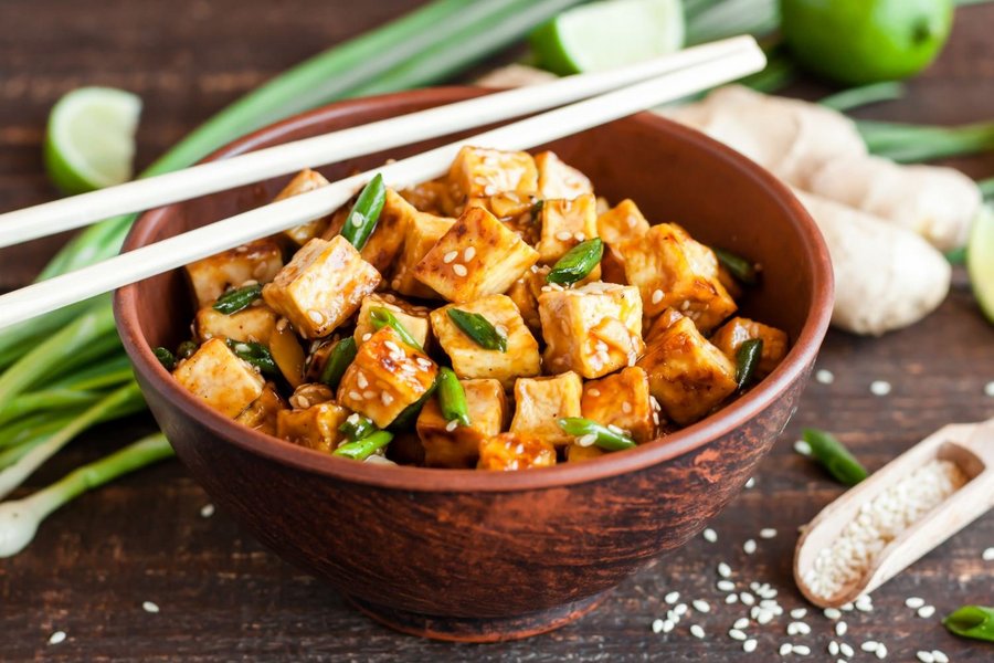 Eine Schüssel mit gebratenem Tofu mit Sesam und Frühlingszwiebeln ist abgebildet.