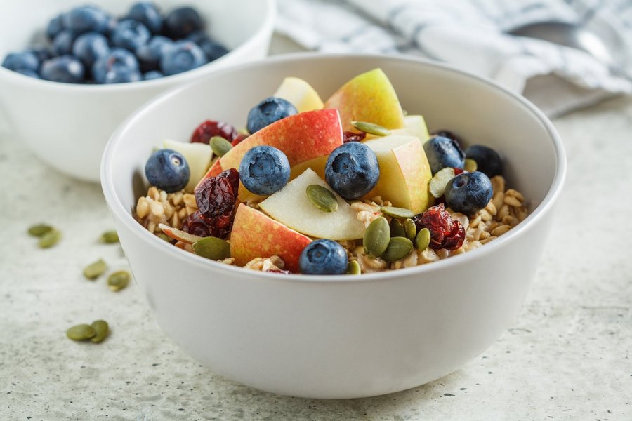 In einer weißen Schüssel befindet sich Müsli mit Obst als Topping.