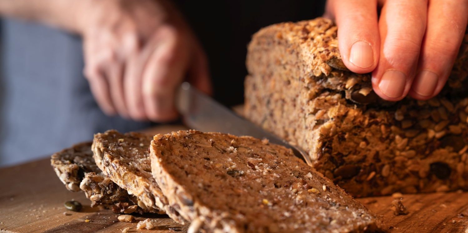 Person schneidet Vollkornbrot.. Artikel "Kohlenhydrate – Power für den Körper" öffnen.