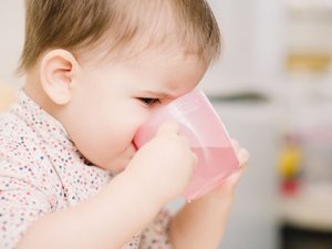 Ein Baby trinkt Wasser aus einem Becher.