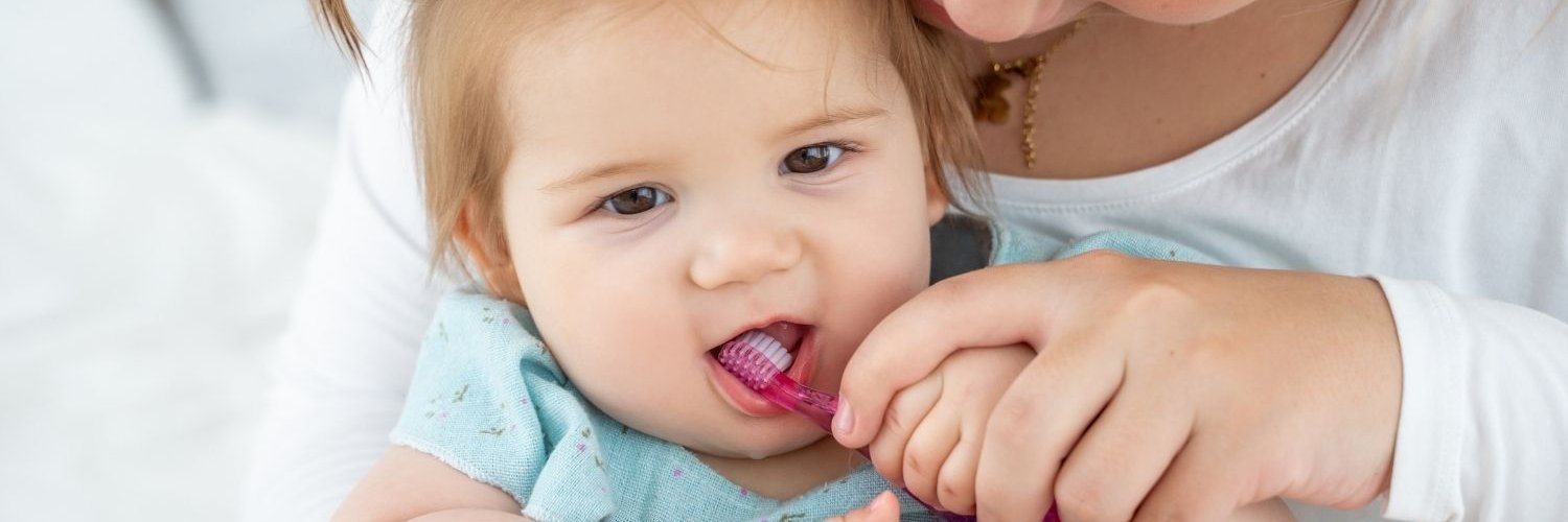 Eine Mutter putzt ihrer etwa einjährigen Tochter die Zähne. 