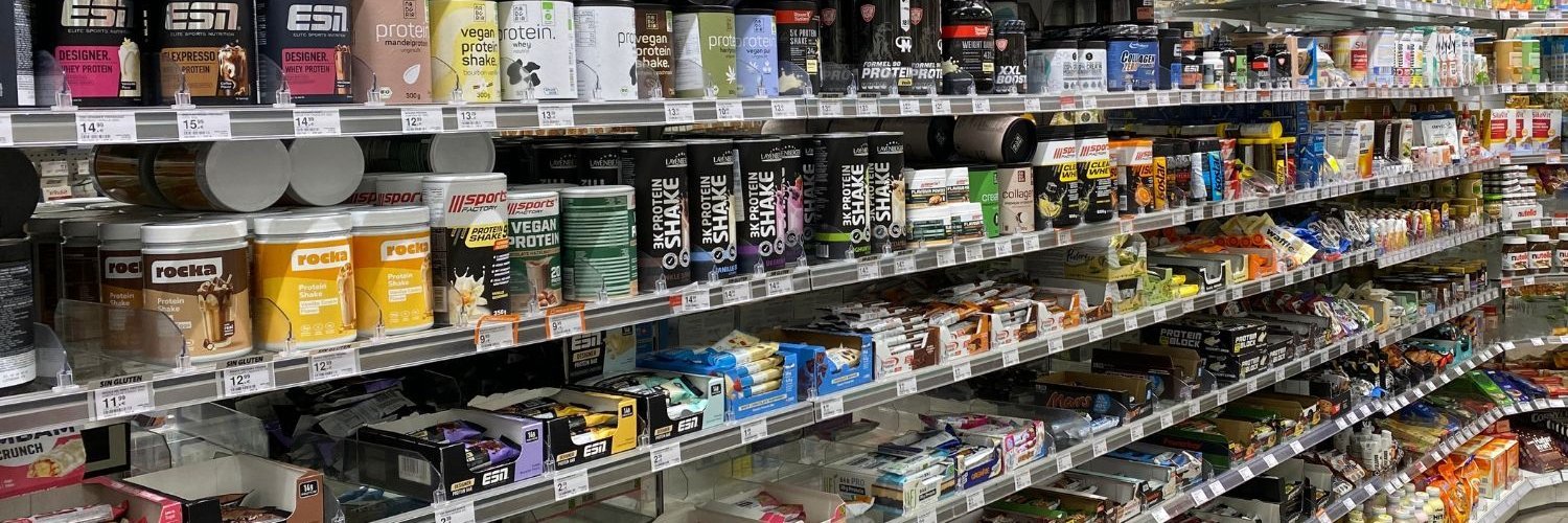 Ein Regal in einem Supermarkt ist gefüllt mit Proteinriegeln und Proteinpulvern. 