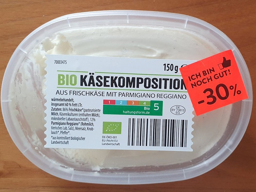 Auf einem Behälter mit Frischkäse klebt ein Aufkleber mit dem Text "Ich bin noch gut, minus 30 Prozent".