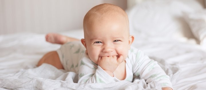 Ein Baby liegt auf einer Decke und lächelt