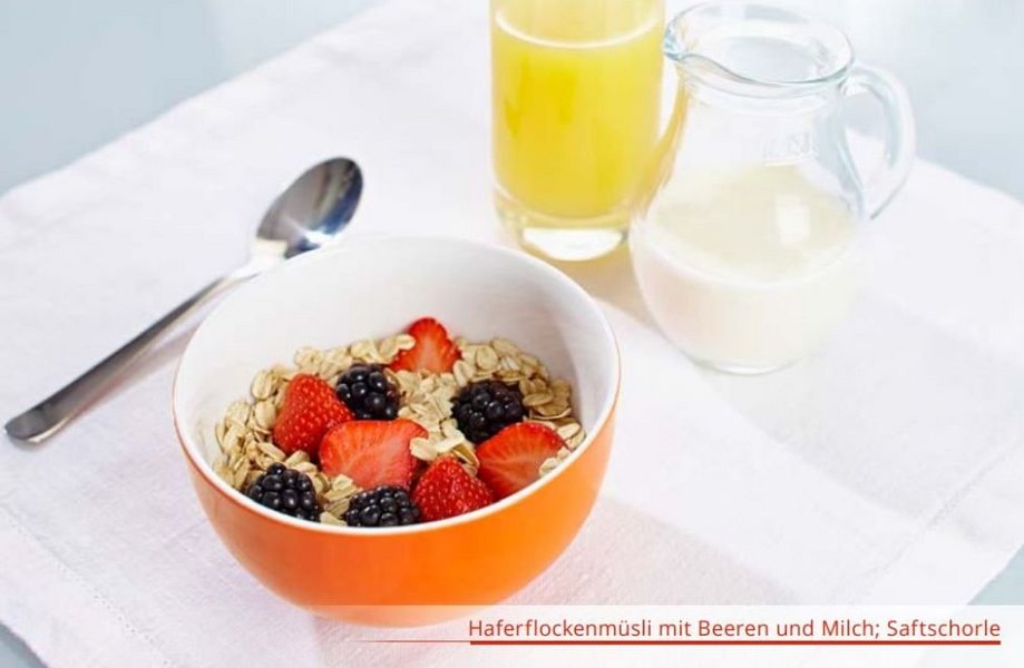 Schale mit Haferflocken und Beeren, Löffel, Glas Orangensaft und einen Krug mit Milch.
