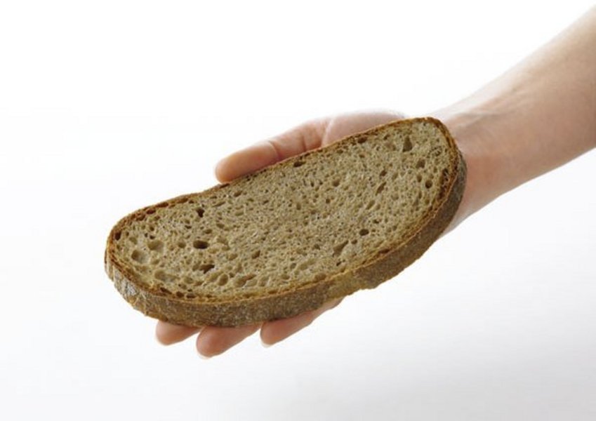 Eine Schreibe Brot liegt auf einer Erwachsenenhand.