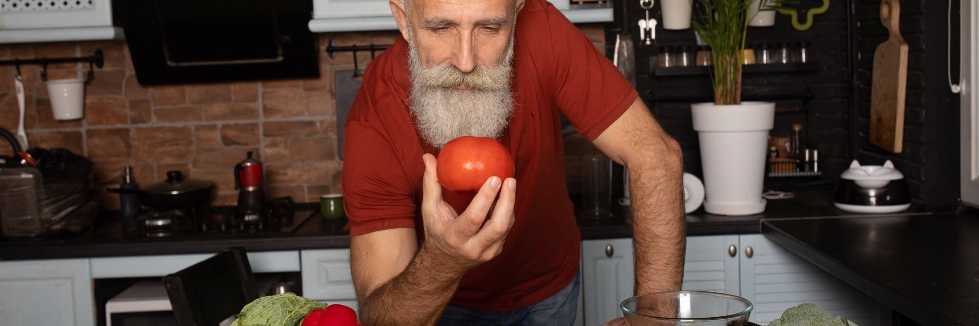 Ein Mann betrachtet eine Tomate in seiner Hand.