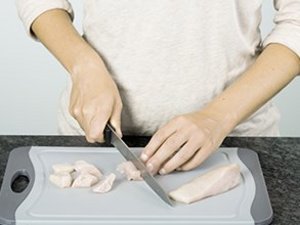 Eine Person schneidet Hähnchenfleisch.