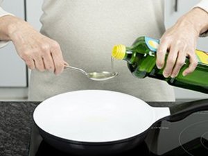 Eine Person gibt Speiseöl in Pfanne.