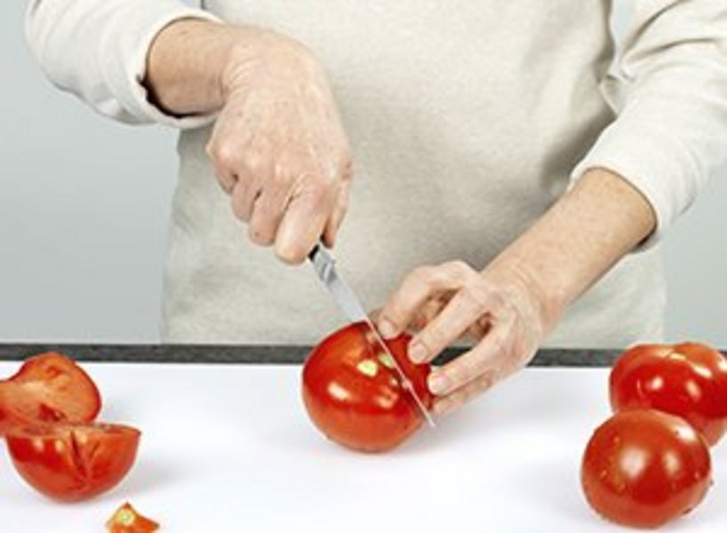 eine Person schneidet eine Tomate.