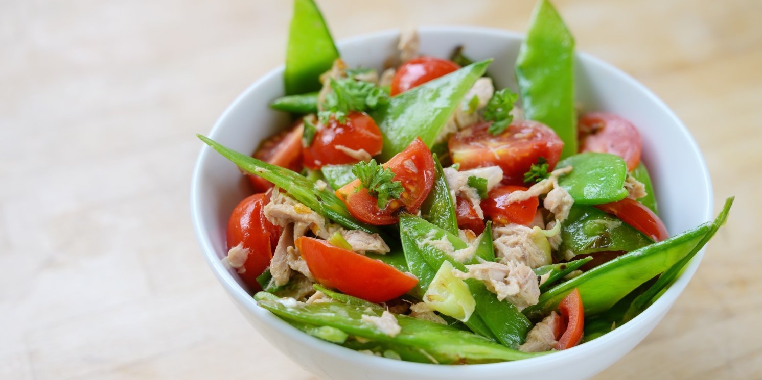 In einer weißen Schüssel ist ein Salat aus Zuckerschoten, Kirschtomaten, Thunfisch und Petersilie angerichtet.. Artikel "Zeit für Zuckerschoten" öffnen.