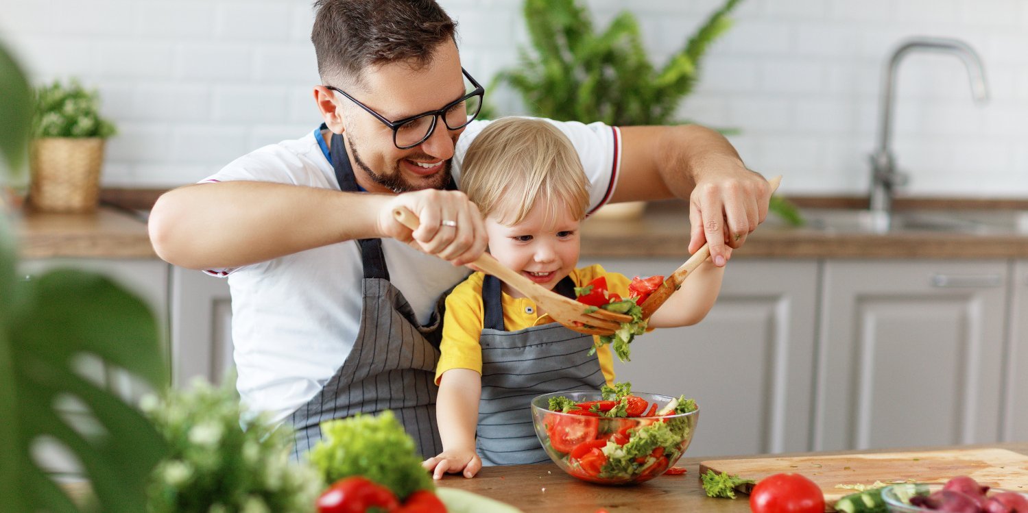 Vater und Sohn mischen zusammen Salat in einer Schüssel.. Artikel "Salate: Gesundheit und Umwelt" öffnen.