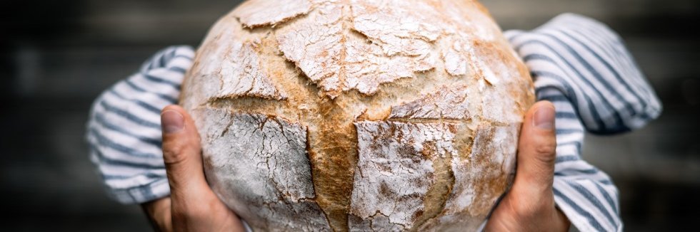 Ein rundes Brot wir in einem Küchentuch eingeschlagen präsentiert.