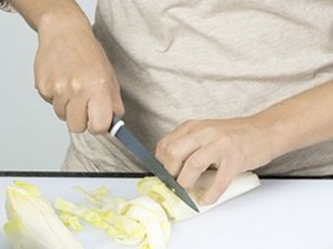 Eine Person schneidet Chicoree in kleine Stücke.