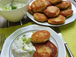 Mehrere vegetarische Bratlinge liegen auf einem Teller mit Kräuterquark und in einer Schüssel.