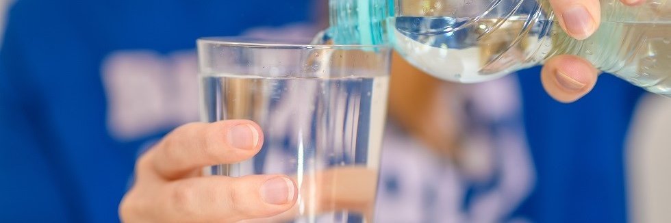 Wasser wird aus einer Flasche in ein Glas eingeschüttet.