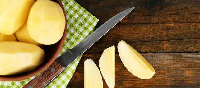 Rohe und geschälte Kartoffeln auf Tuch mit Messer